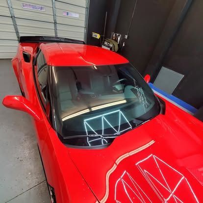 A high-angle view of a shiny red sports car parked inside a garage.