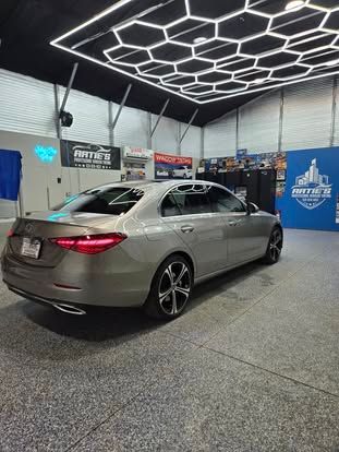 A silver Mercedes-Benz sedan parked inside a well-lit garage with a hexagonal ceiling light pattern.