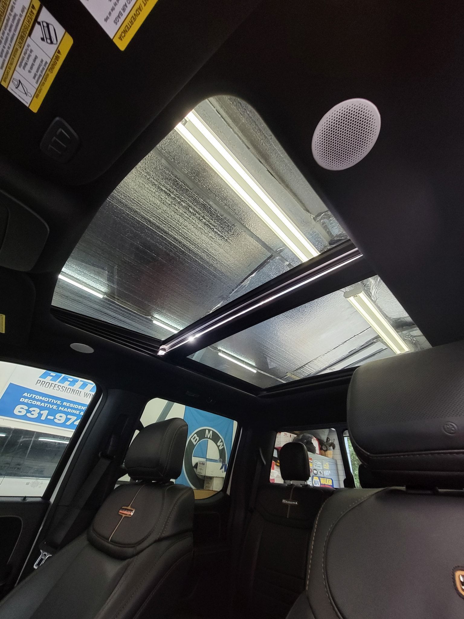 A low-angle view of a vehicle's interior showing a large panoramic glass sunroof and dark leather seats.