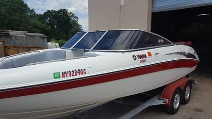 A white and red Yamaha jet boat on a trailer, parked next to a building.