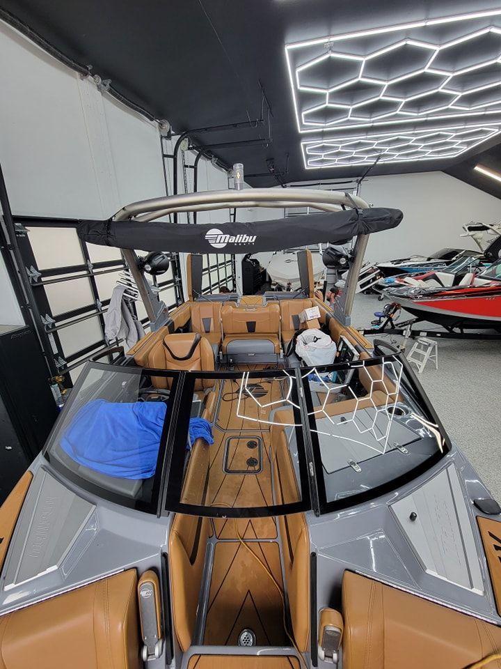 A view looking down into the cockpit of a modern boat with tan leather seating, wood-look decking, and a metal frame tower.