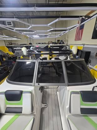 Interior view of a boat with gray, white, and lime green seating, a dark windshield, and a geometric overhead light rack.