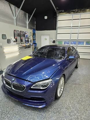A blue BMW sedan parked inside a brightly lit professional auto detailing garage.
