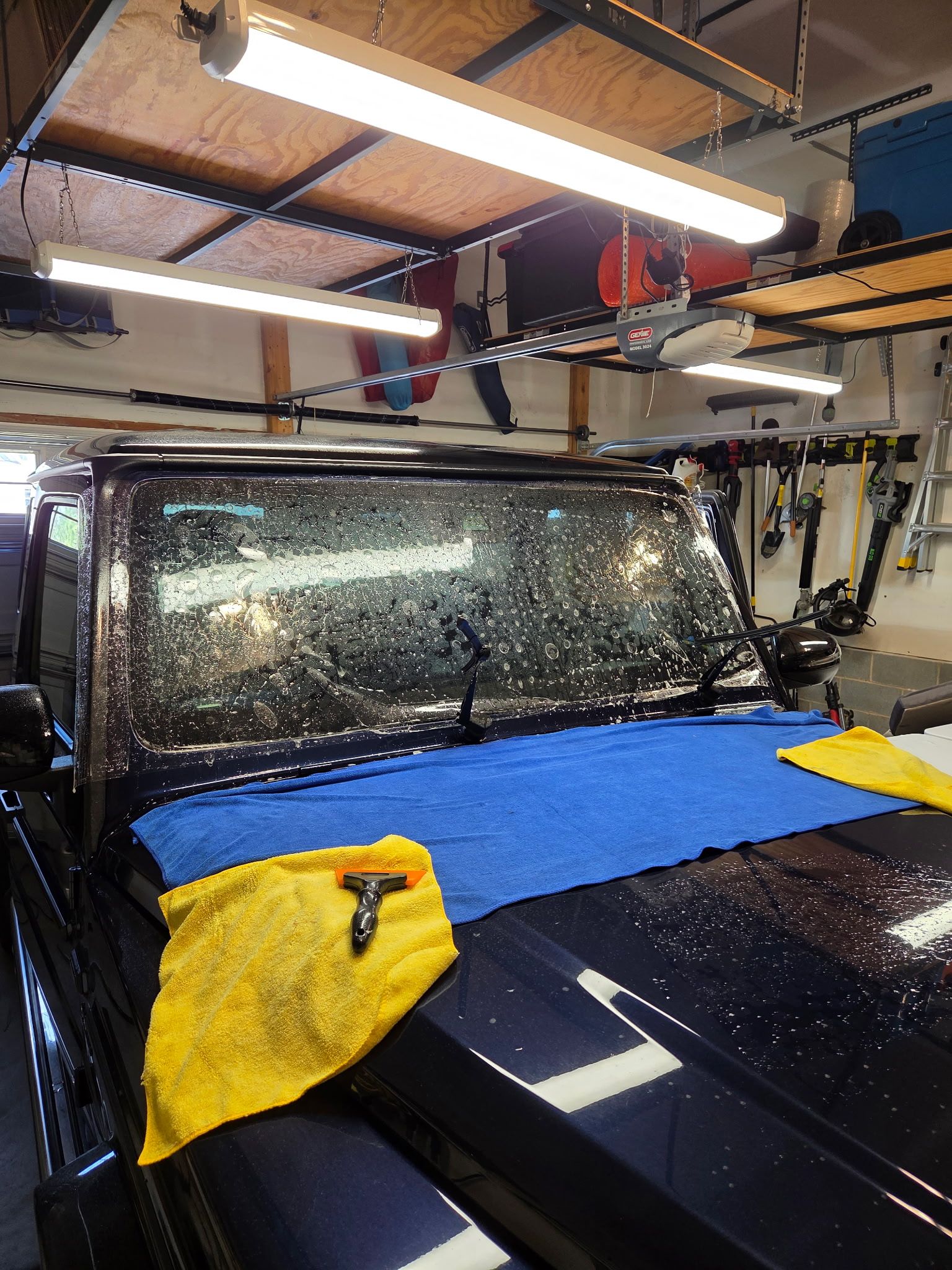 A white Volkswagen Golf with a black roof parked inside a well-lit garage with a speckled floor.
