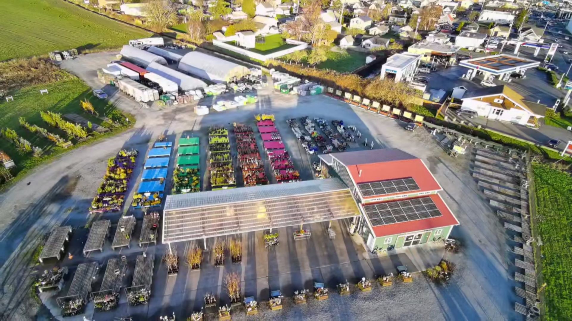 Aerial view of an industrial site with trucks, buildings, and parked machinery. Solar panels on a red roof.