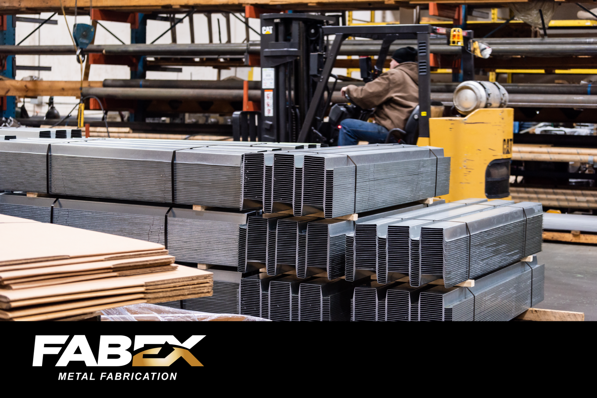 Worker operating forklift beside stacked metal beams in an industrial warehouse, with FABEX logo at bottom left