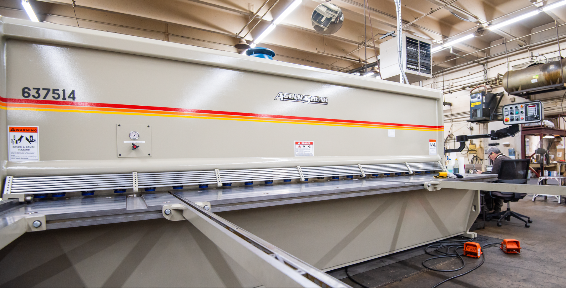Large white industrial machine with orange stripe in a factory workshop