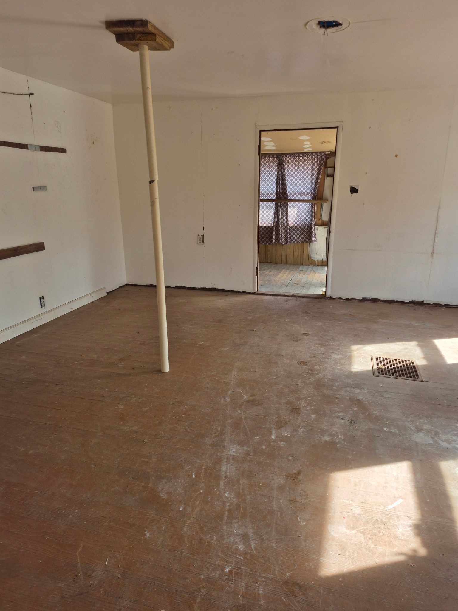 Dilapidated shed interior, concrete floor, open front, view of target practice area, dry foliage.