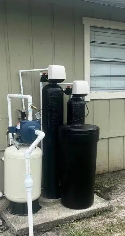 Outdoor water filtration tanks and pipes beside a house wall