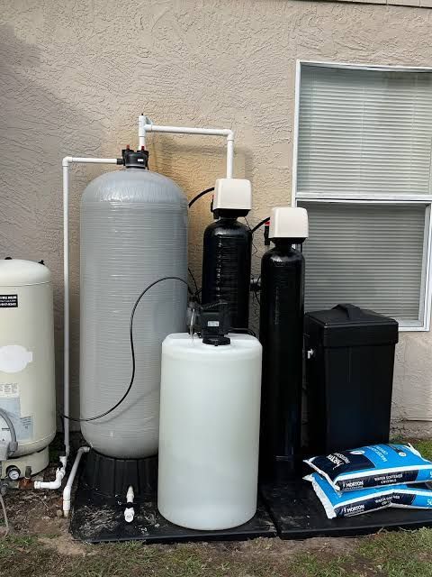 Water treatment system with multiple tanks and filters beside a house exterior