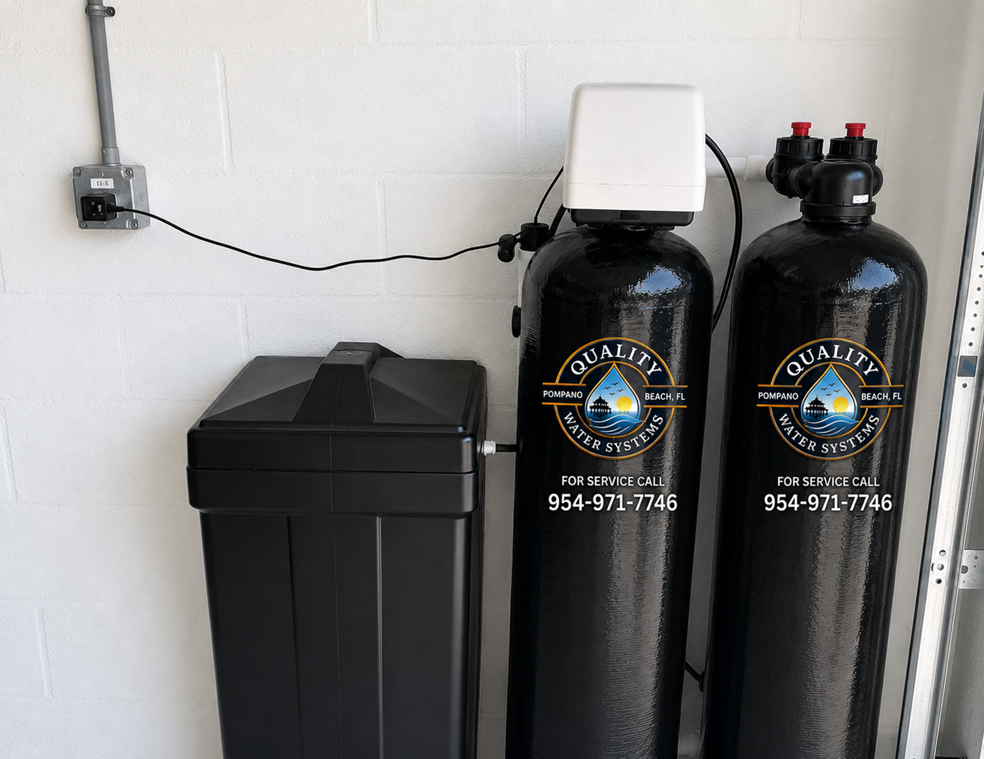 Black water softener tanks and a trash bin against a white wall in a utility room
