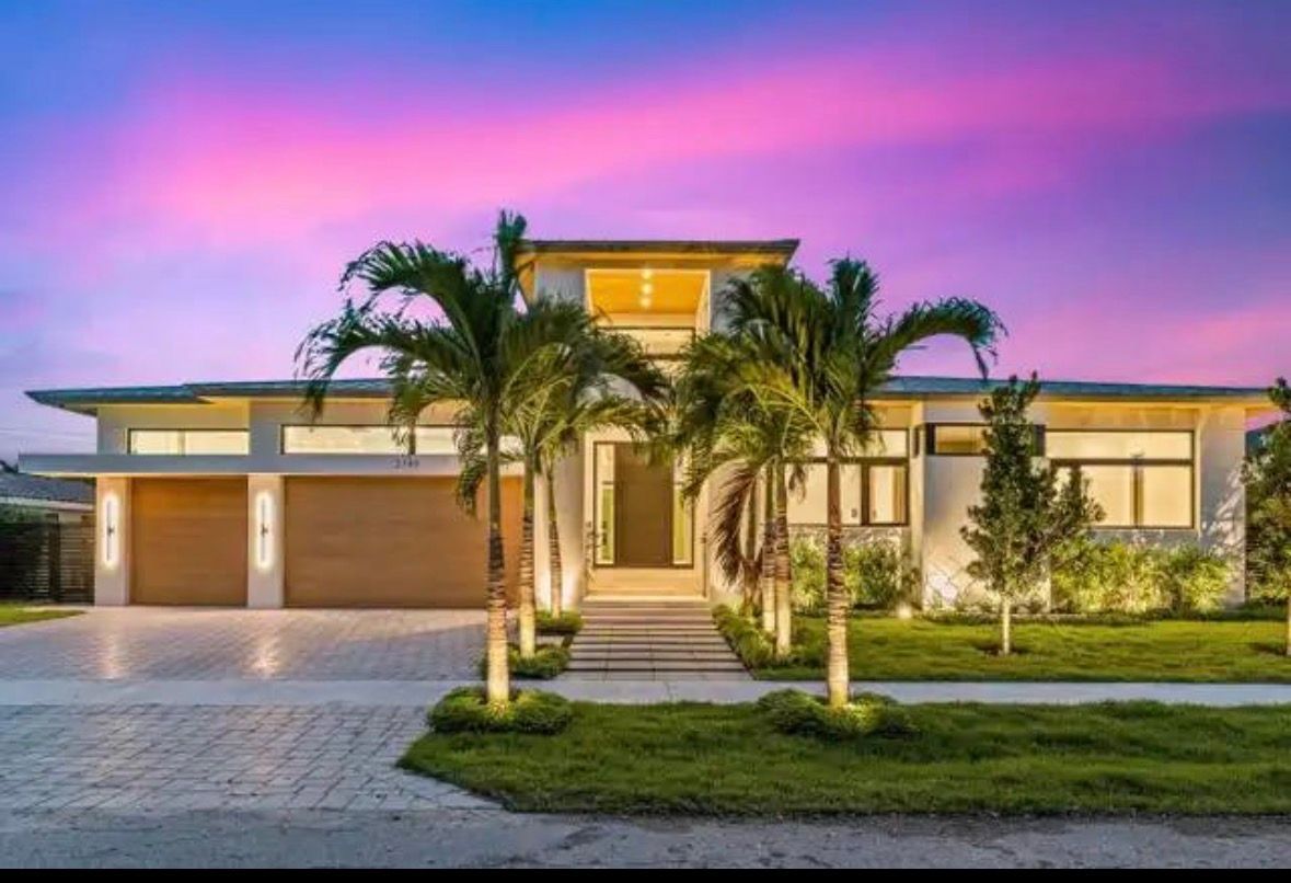 Modern luxury house with palm trees and a colorful sunset sky