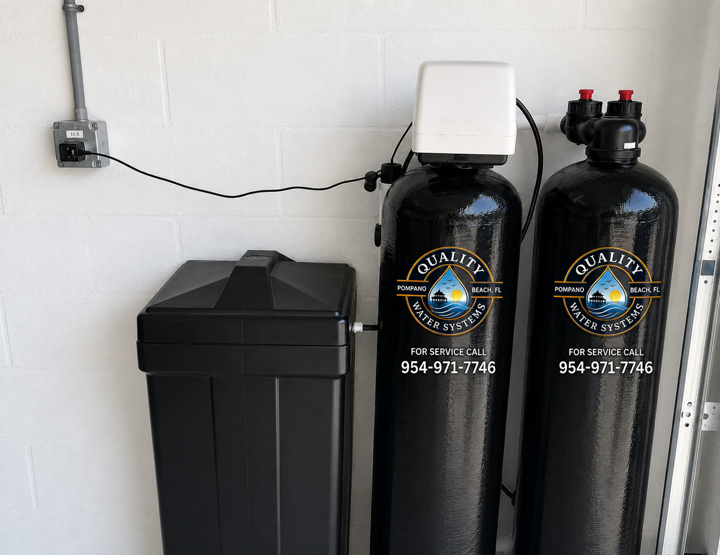 Water softener system with a black cabinet and two tall black tanks against a white wall.