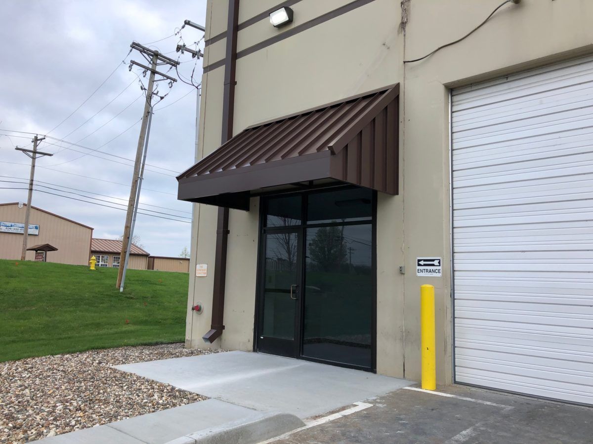 A building with a brown awning over the door and a white garage door.