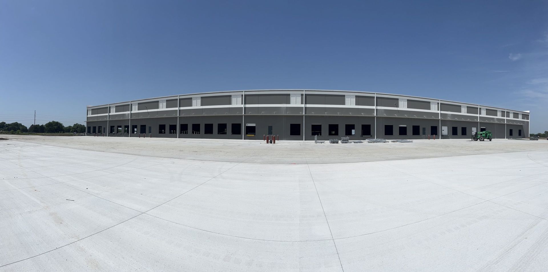 A large building under construction with a white roof and a blue sky in the background.