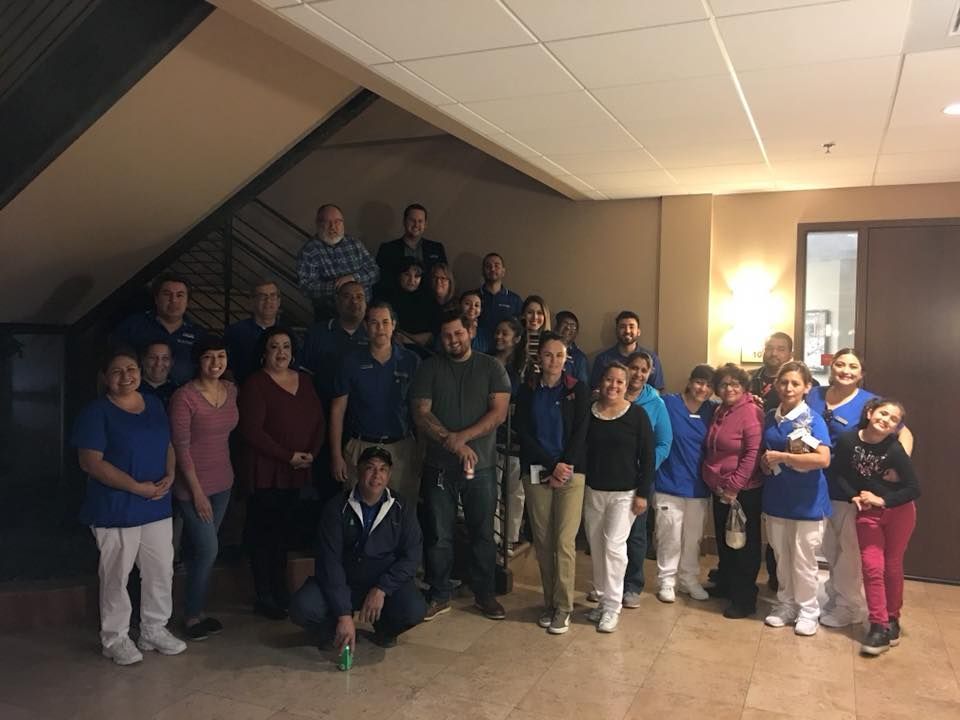 A group of people standing together for a photo in an indoor stairwell with beige walls.