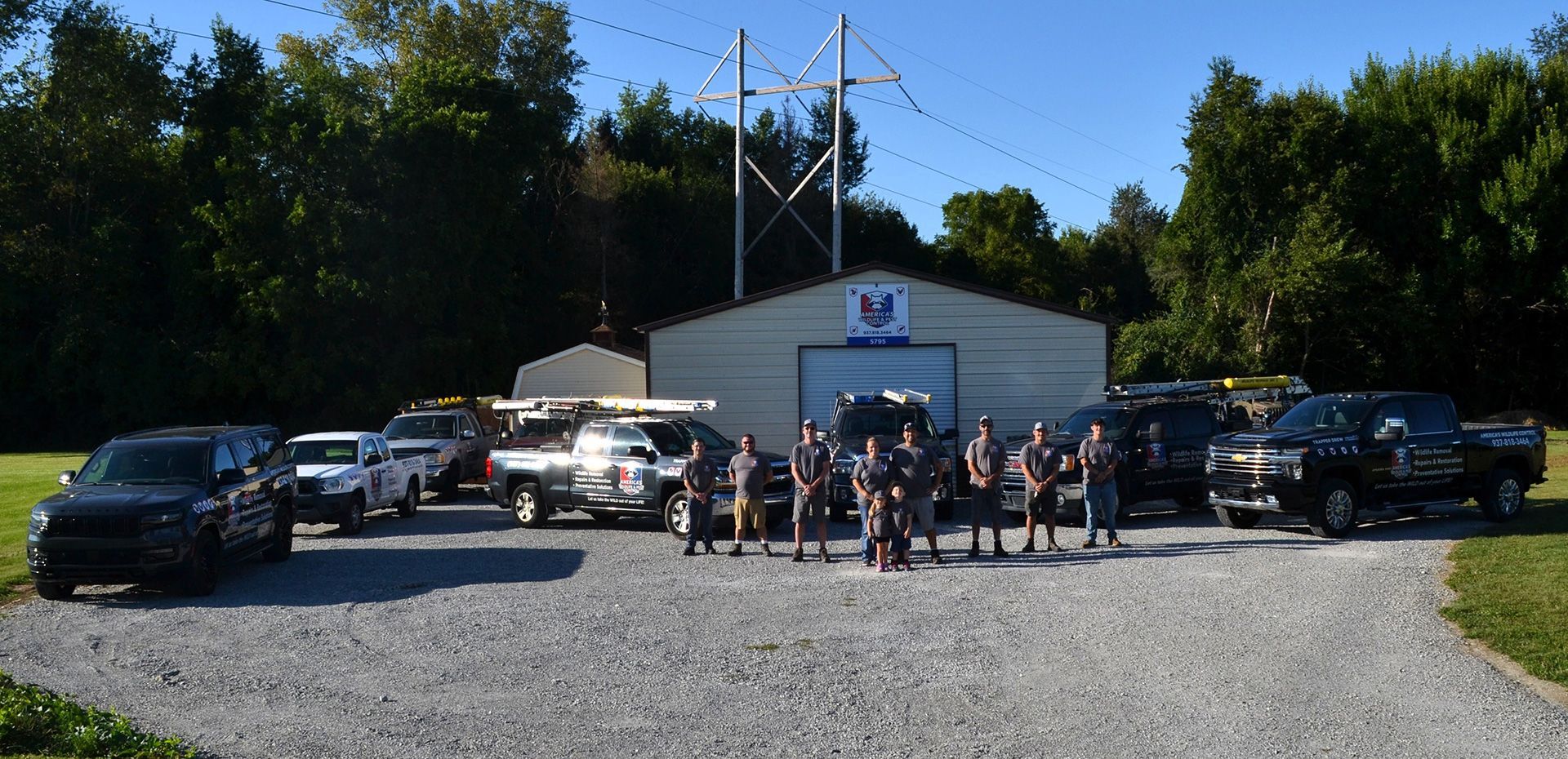 Group of people and vehicles in front of a building under a power line.