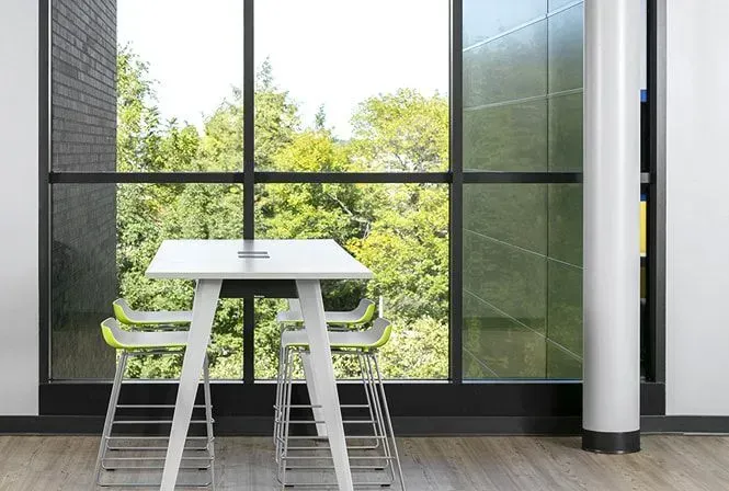 White table and stools near a large window overlooking trees.
