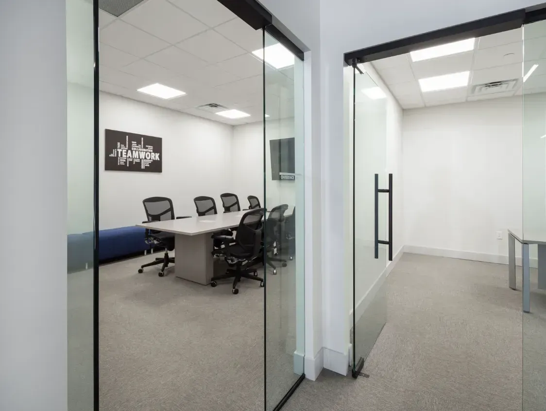 Glass-walled office space with conference room visible through open door.