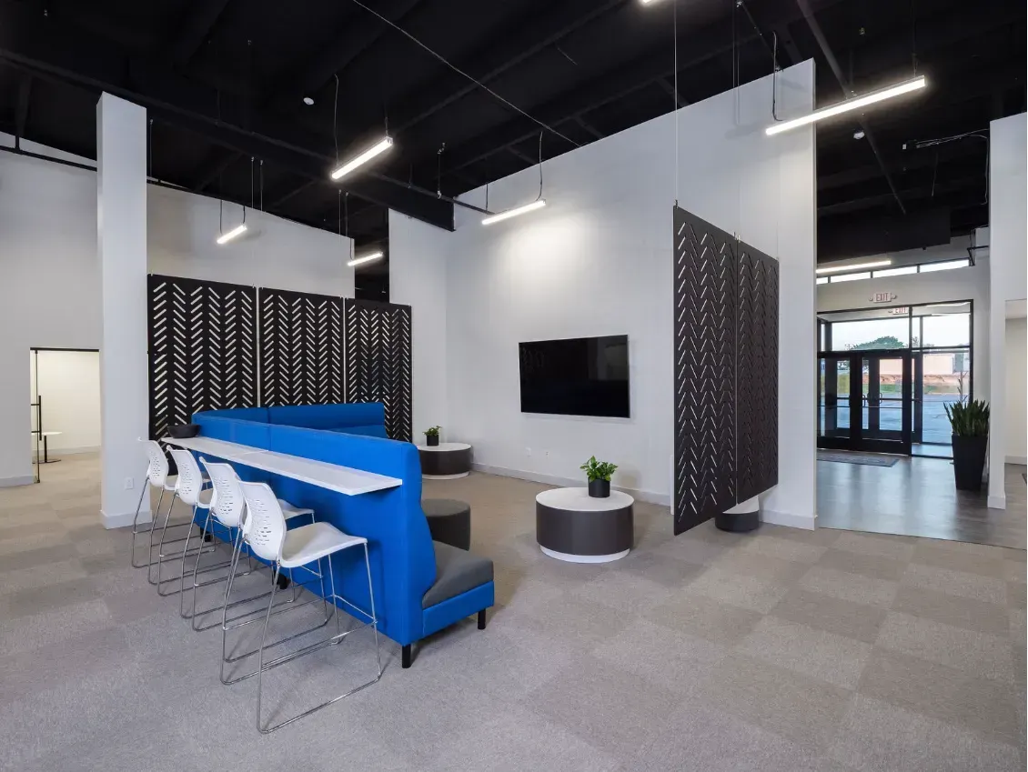 Modern office waiting area with blue seating, a large TV, and patterned divider panels.