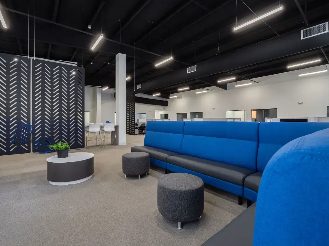 Modern office interior with blue seating, patterned screen, and black ceiling.