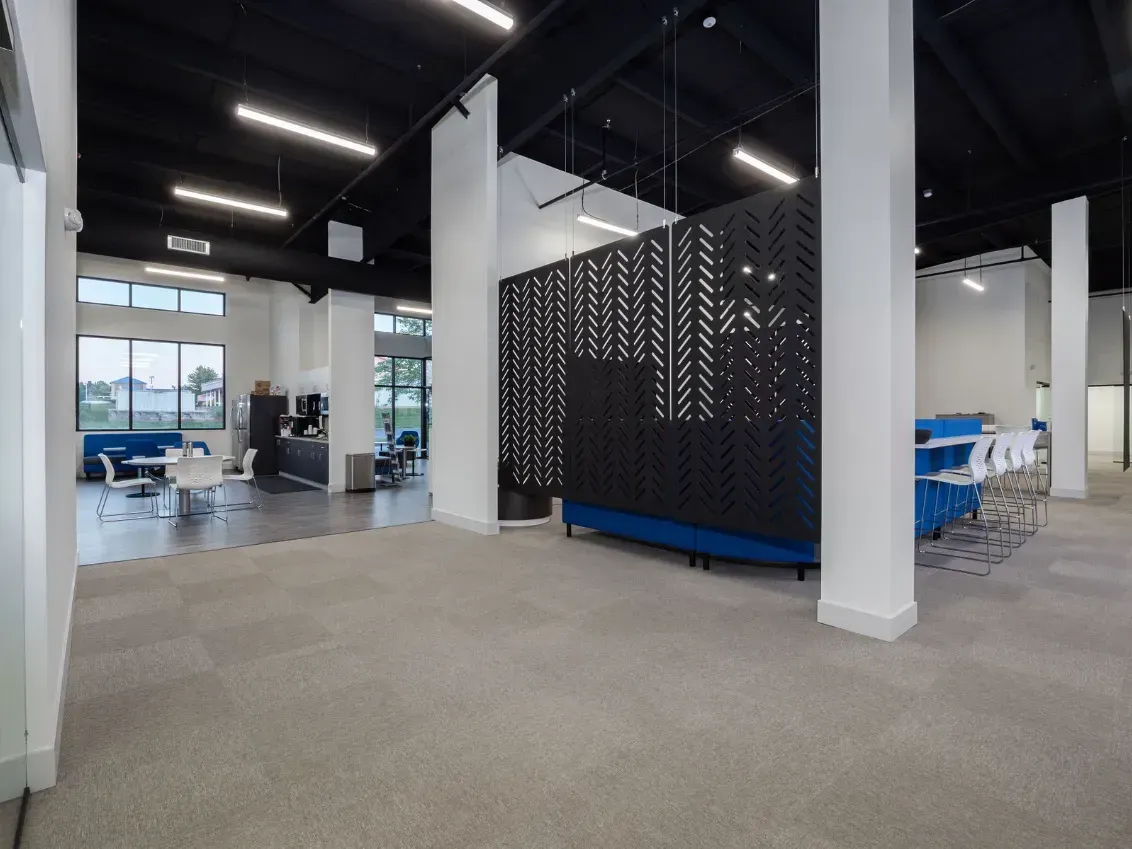 Open, modern office space with white pillars, blue accents, and a patterned room divider.