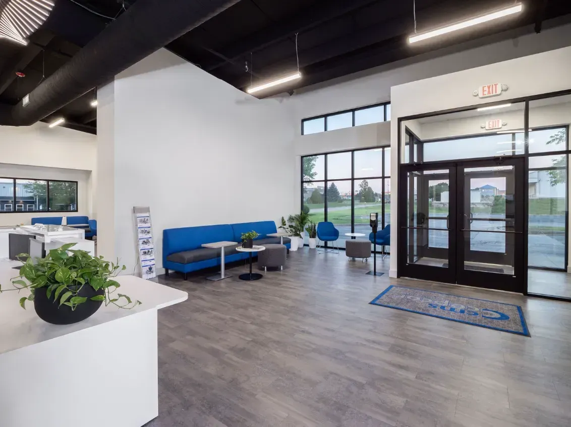 Modern office lobby with blue seating, large windows, and double doors.