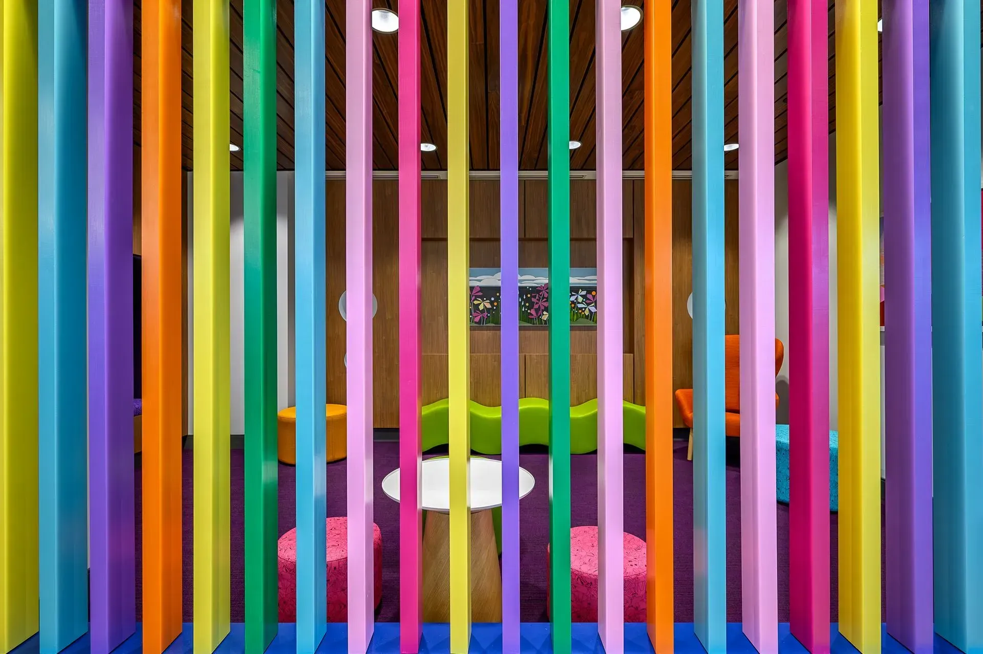 Colorful vertical stripes creating a playful room divider; interior with furniture visible beyond.