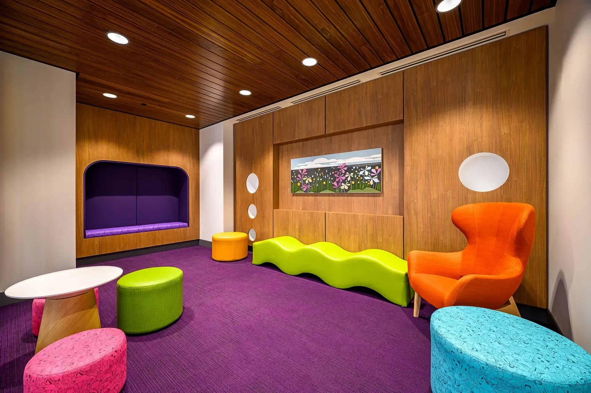 Colorful kids' play area with purple carpet, wooden paneling, and vibrant furniture.