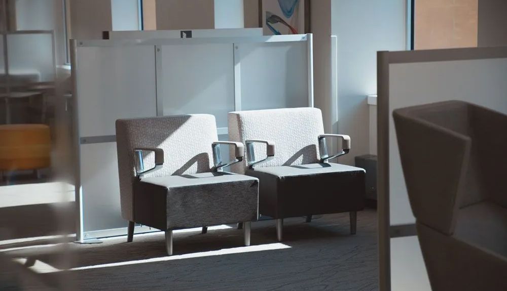 Interior of a restaurant with a bar and tables. Neutral tones, modern decor, overhead lights, empty.