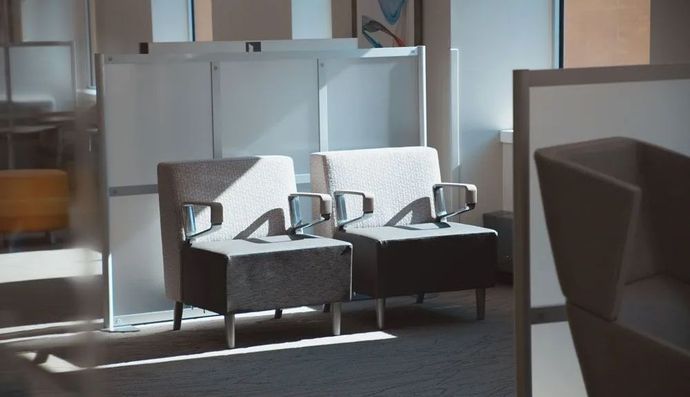 Restaurant interior with bar, tables, chairs; neutral tones, modern design, decorative lights.