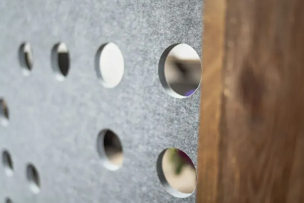 Gray panel with circular holes, attached to a wooden beam.