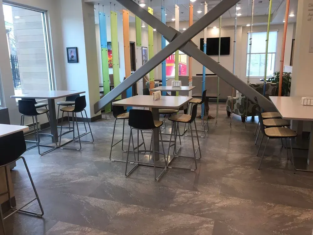 Modern cafe interior with tables, chairs, and colorful vertical panels; natural light.