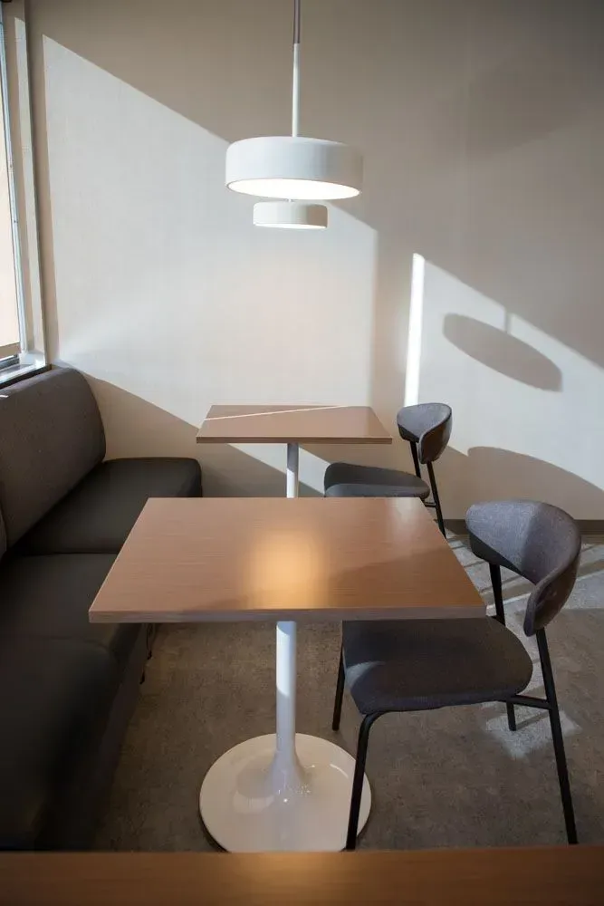 A cafe seating area with tables, chairs, a built-in bench, and a modern light fixture.