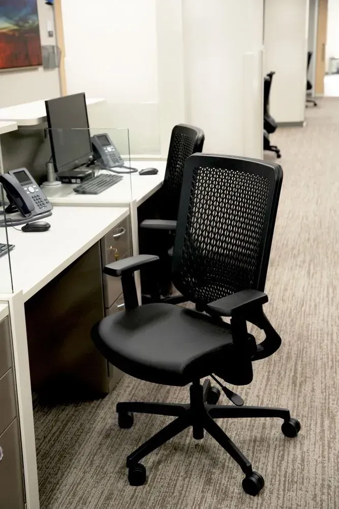 Black mesh office chair in a bright office setting.