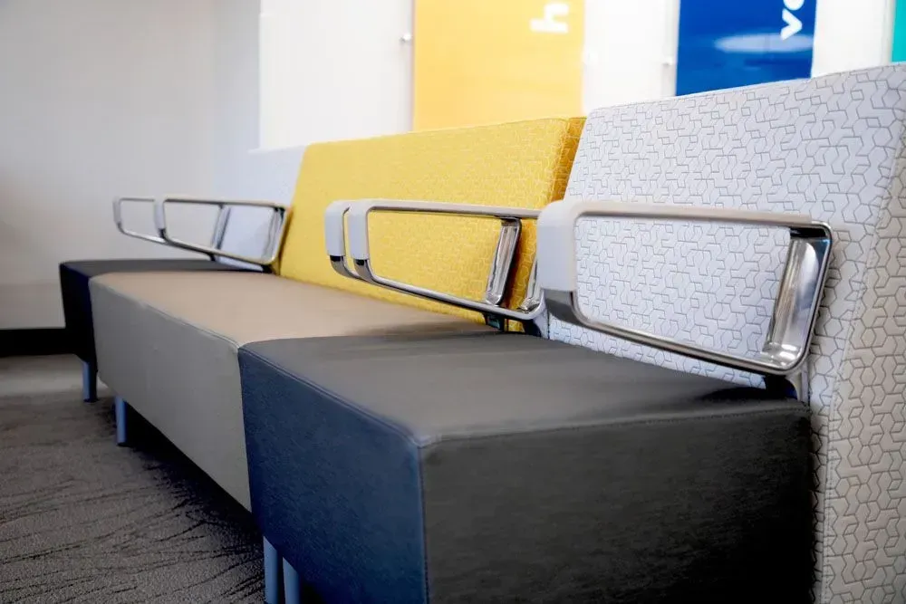 Modular office seating; gray, yellow, and patterned fabric with metal armrests.
