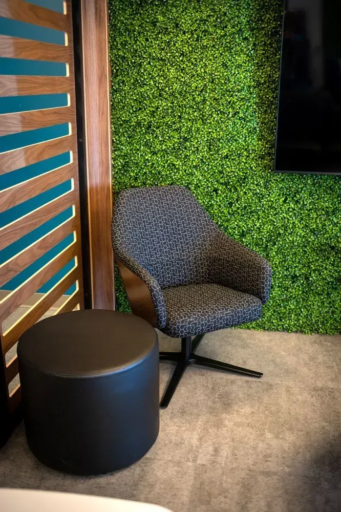 Chair and ottoman in front of a green wall, next to a wooden slat wall.