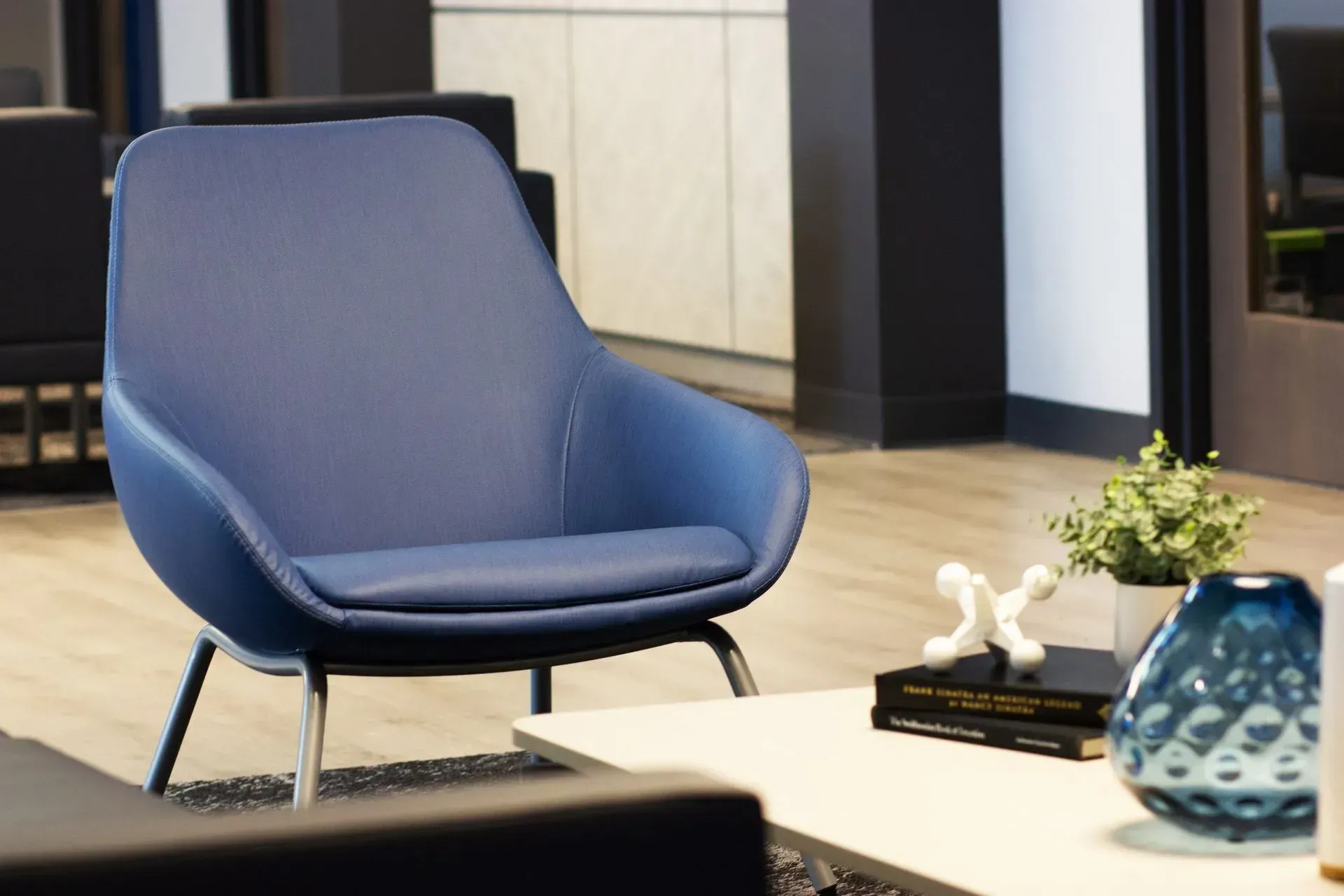 Blue armchair with silver legs, near a small table with decor, in a modern setting.