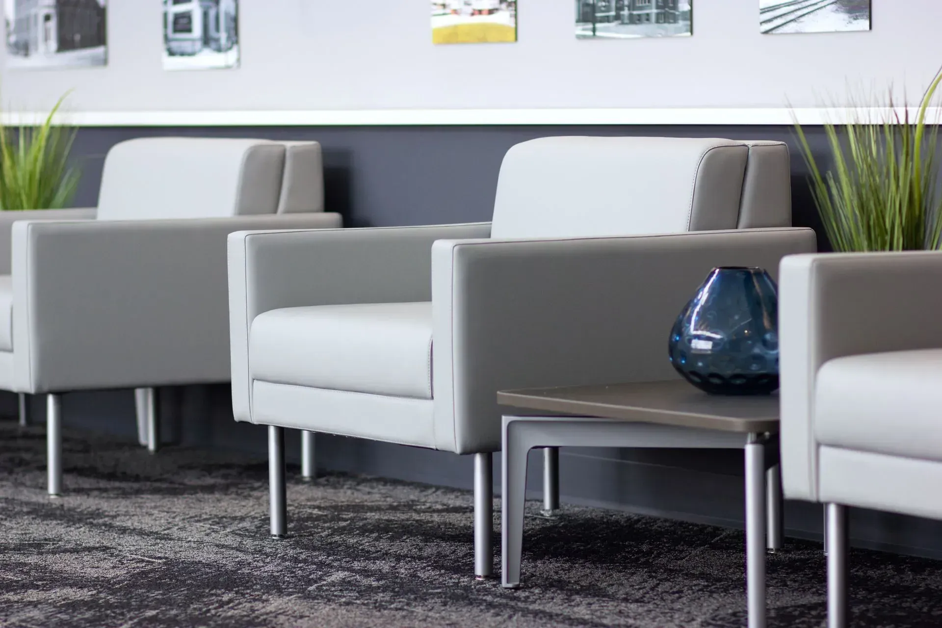 Modern waiting area with gray chairs, small table, and a blue vase.