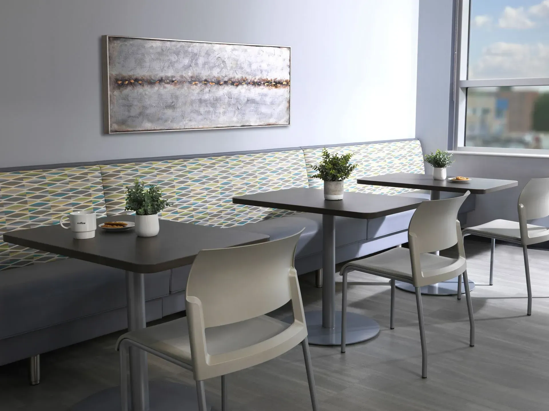 Canteen area with dark tables, chairs, and a built-in bench. Artwork hangs above the bench.