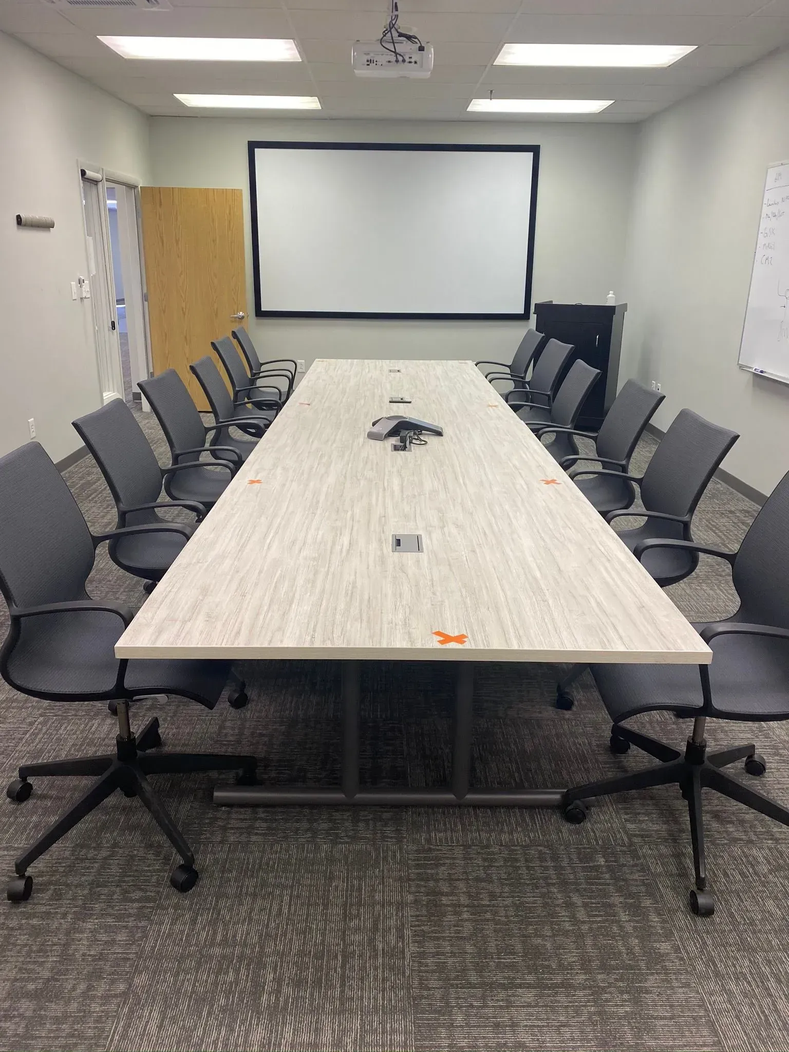 Conference room with long table, chairs, projection screen, and a projector.