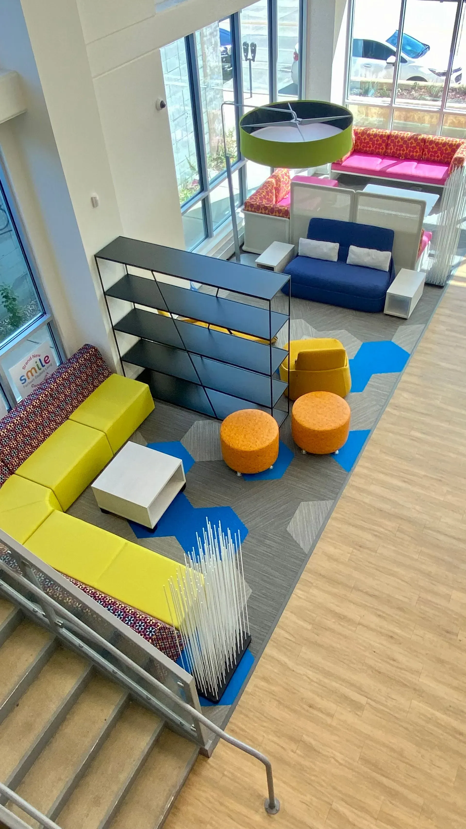 Modern library interior with colorful seating, bookshelves, and large windows.
