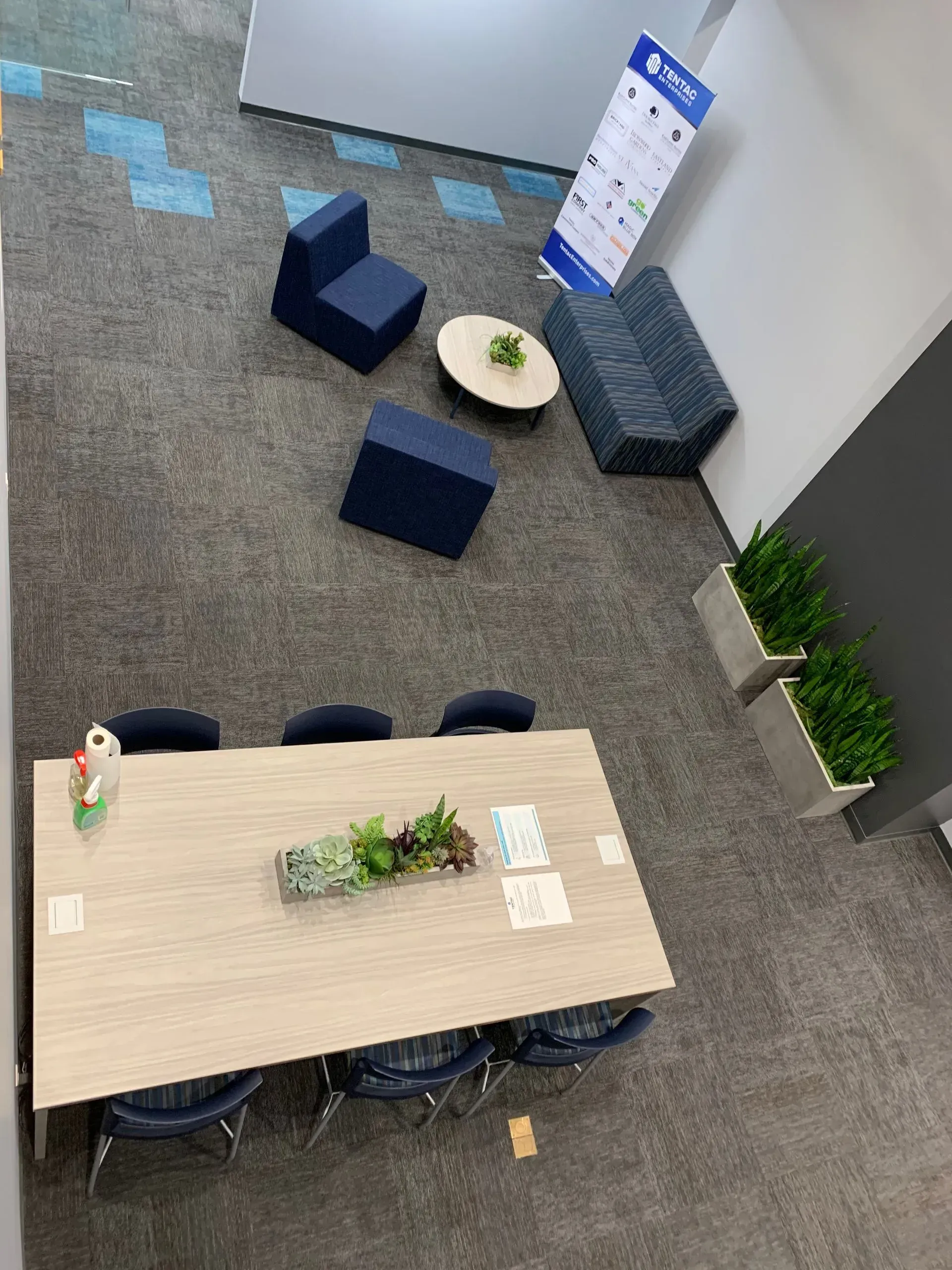 Office seating area with a table, chairs, and couches. Blue and gray tones.