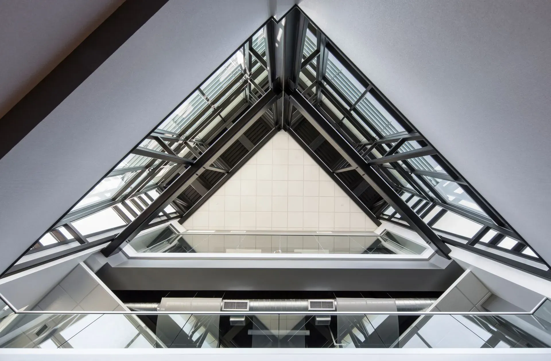 Triangular skylight in modern building with glass panes and metal framework.