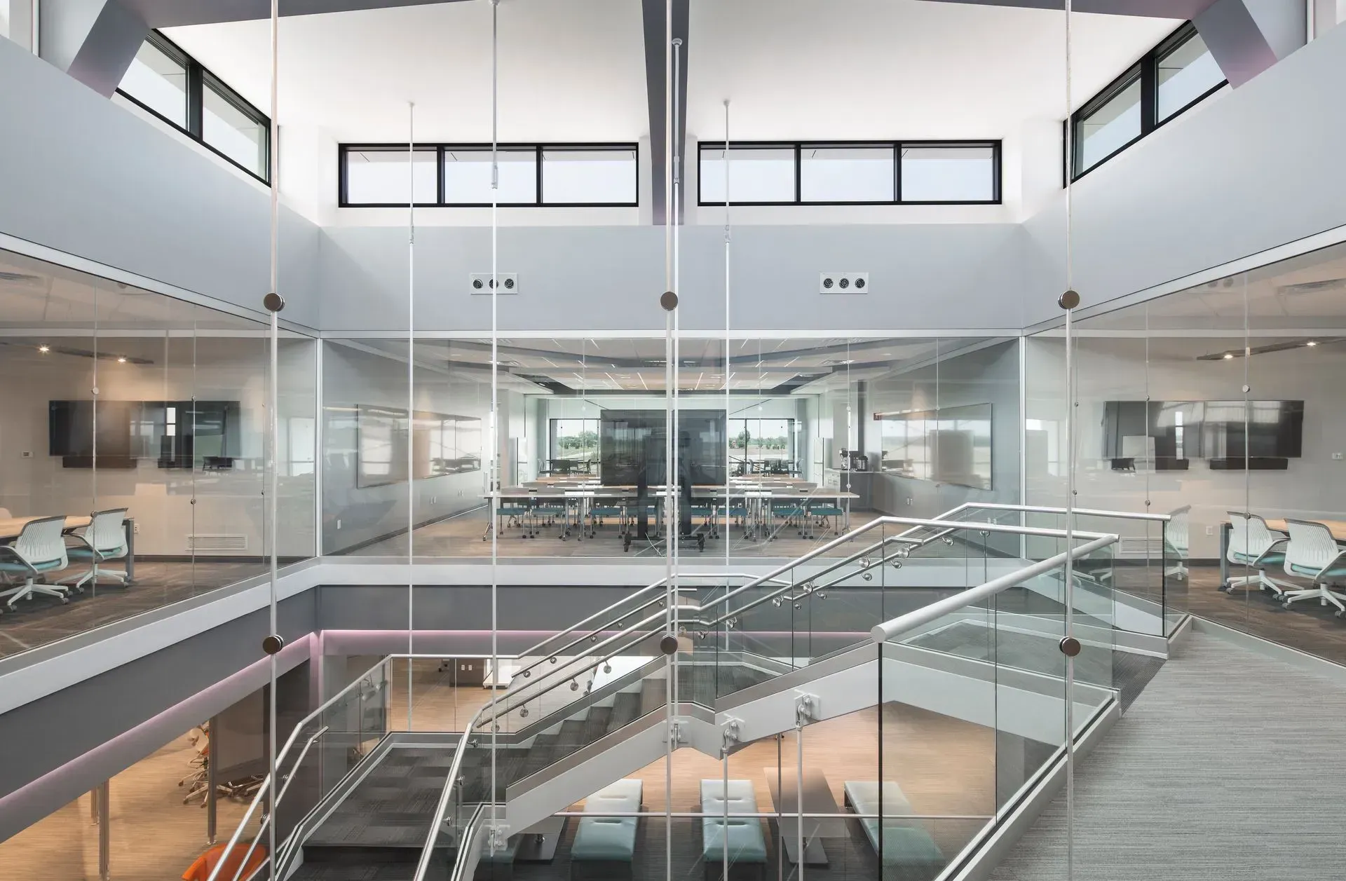 Modern office interior with glass walls, multiple levels, and a central staircase.
