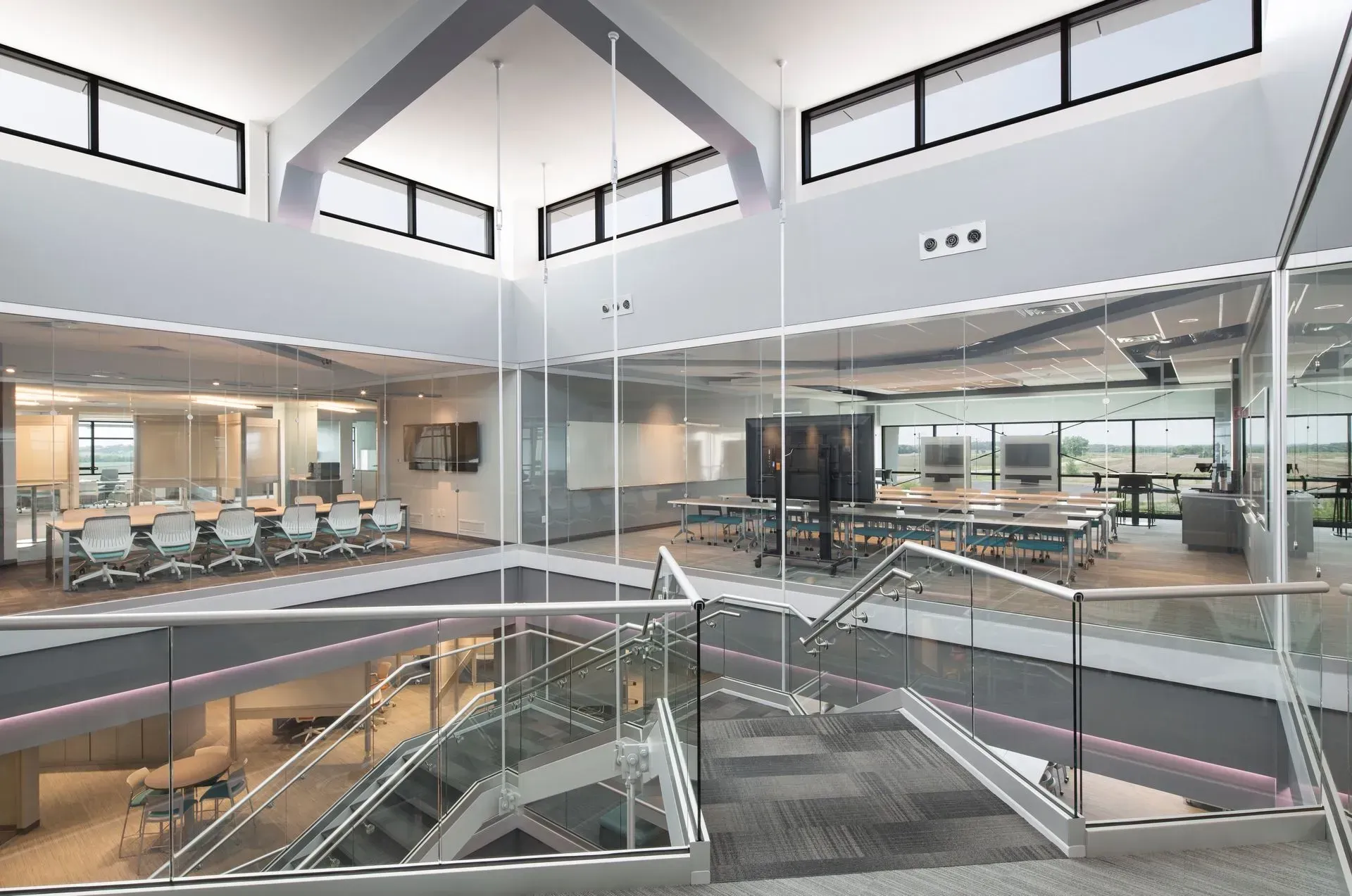 Modern office interior with glass walls, multiple levels, and a staircase.