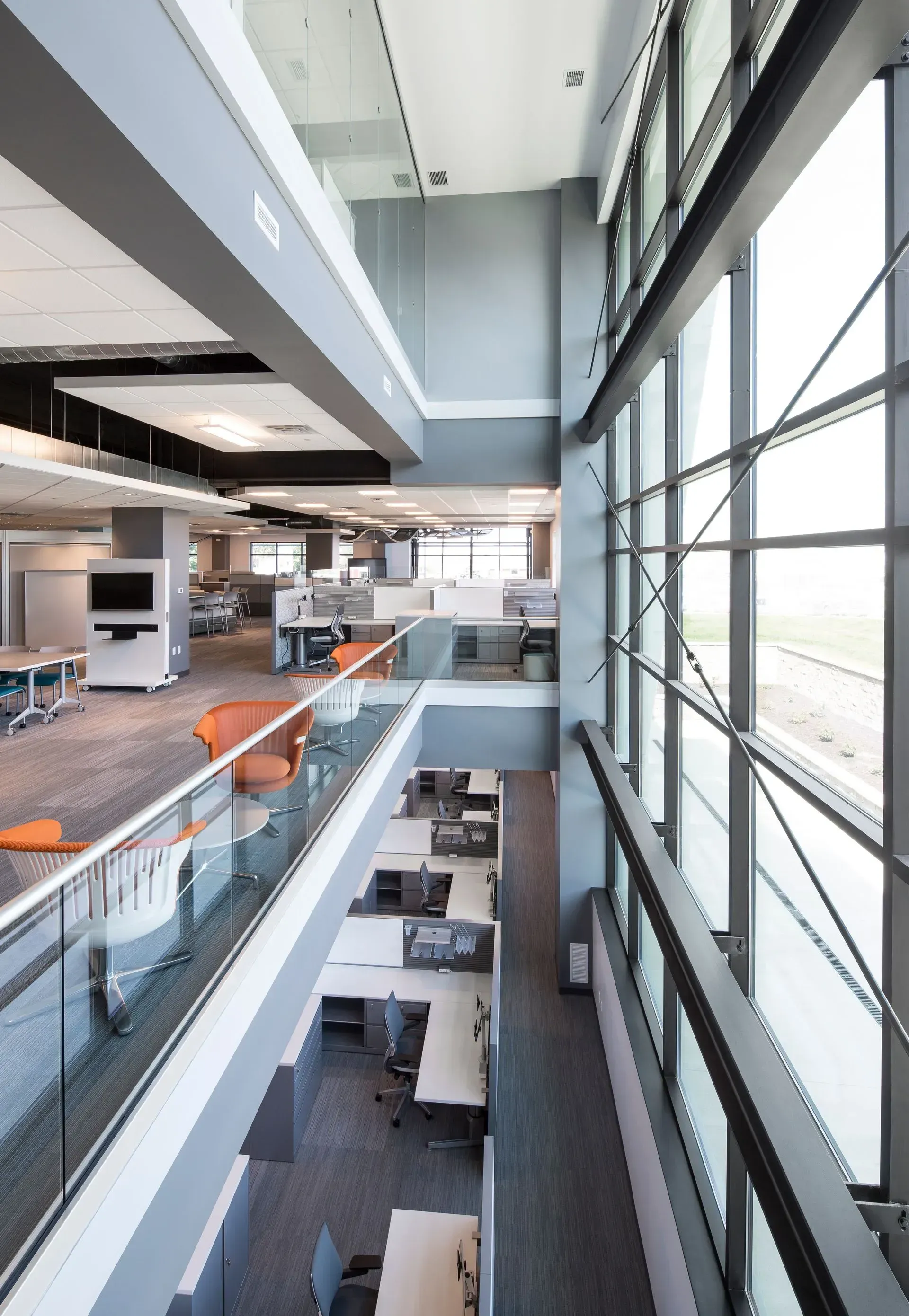 Interior office space with multi-level work areas, large windows, and modern furnishings.