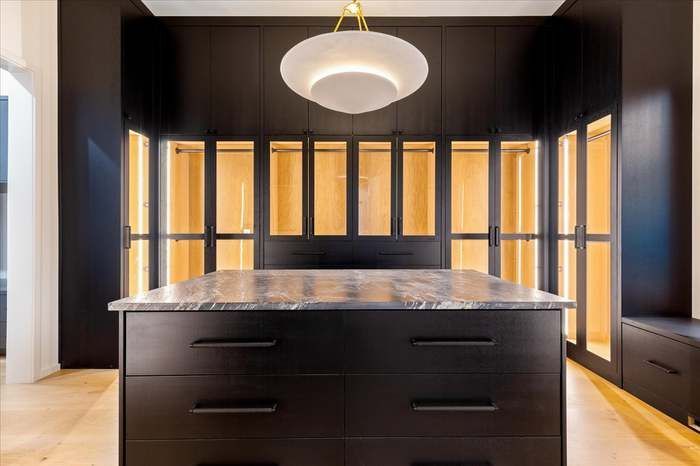 A large walk in closet with a large island in the middle.