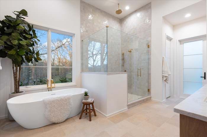 A bathroom with a tub , shower , sink and window.