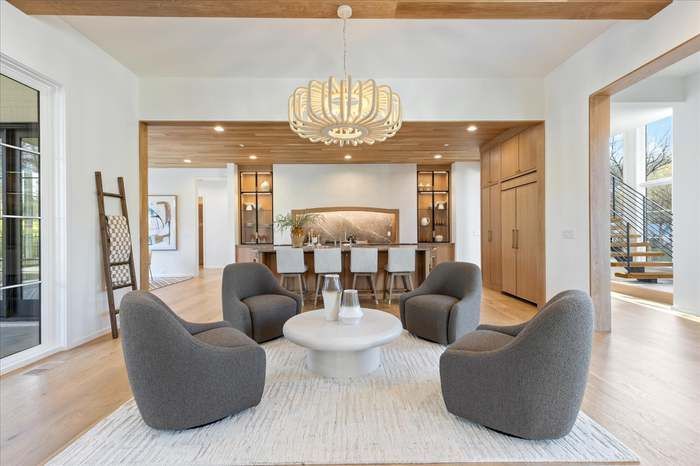 A living room with chairs , a coffee table and a chandelier.